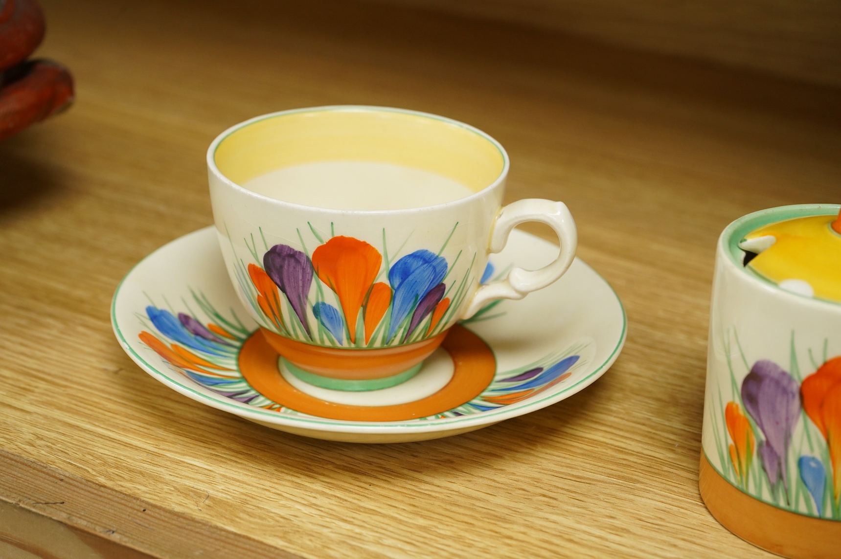 A Clarice Cliff ‘crocus’ pattern preserve jar and cover, 10cm high and a similar cup and saucer